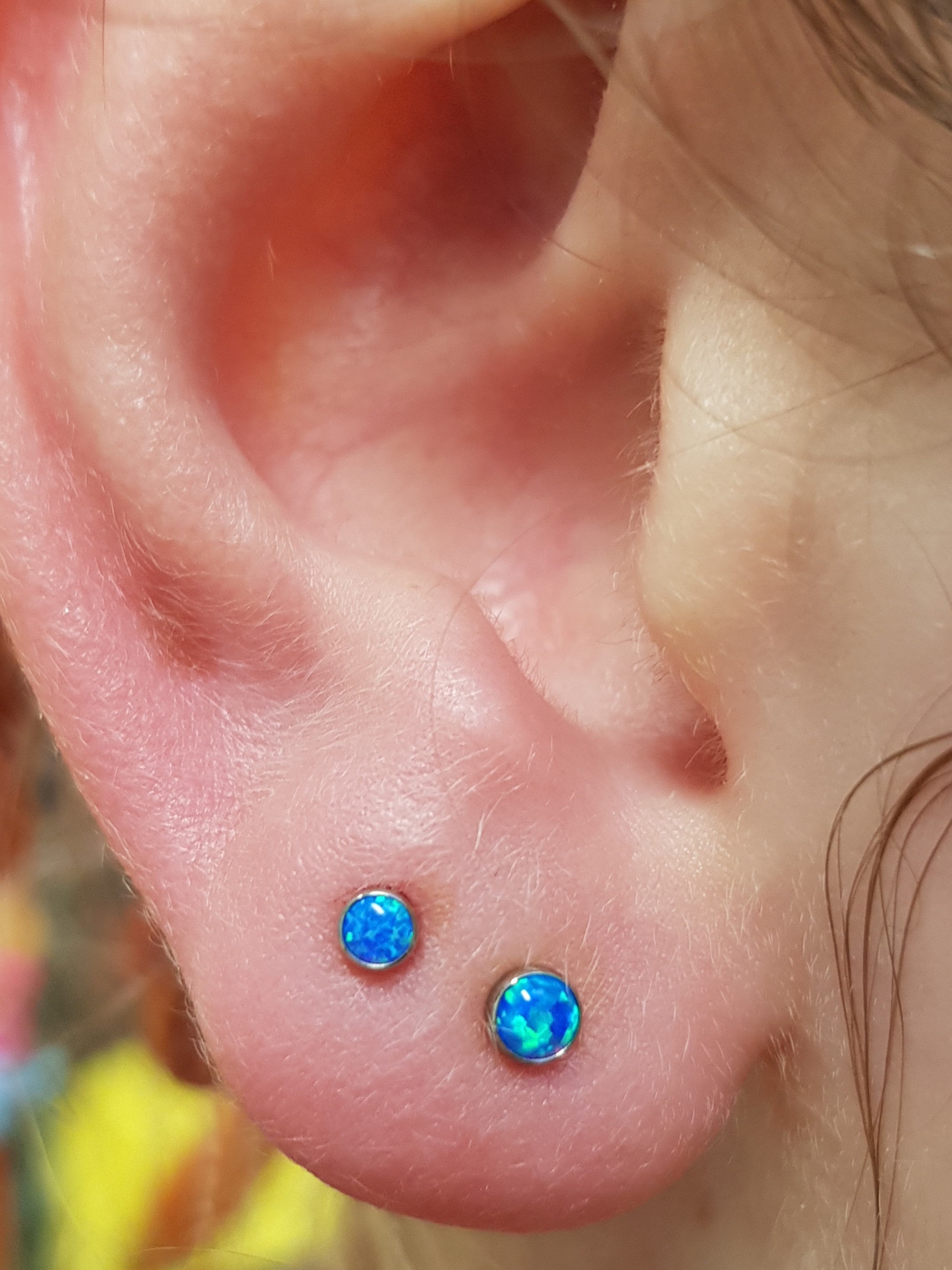 double lobe piercing on a child's ears with blue opals in implant grade titanium