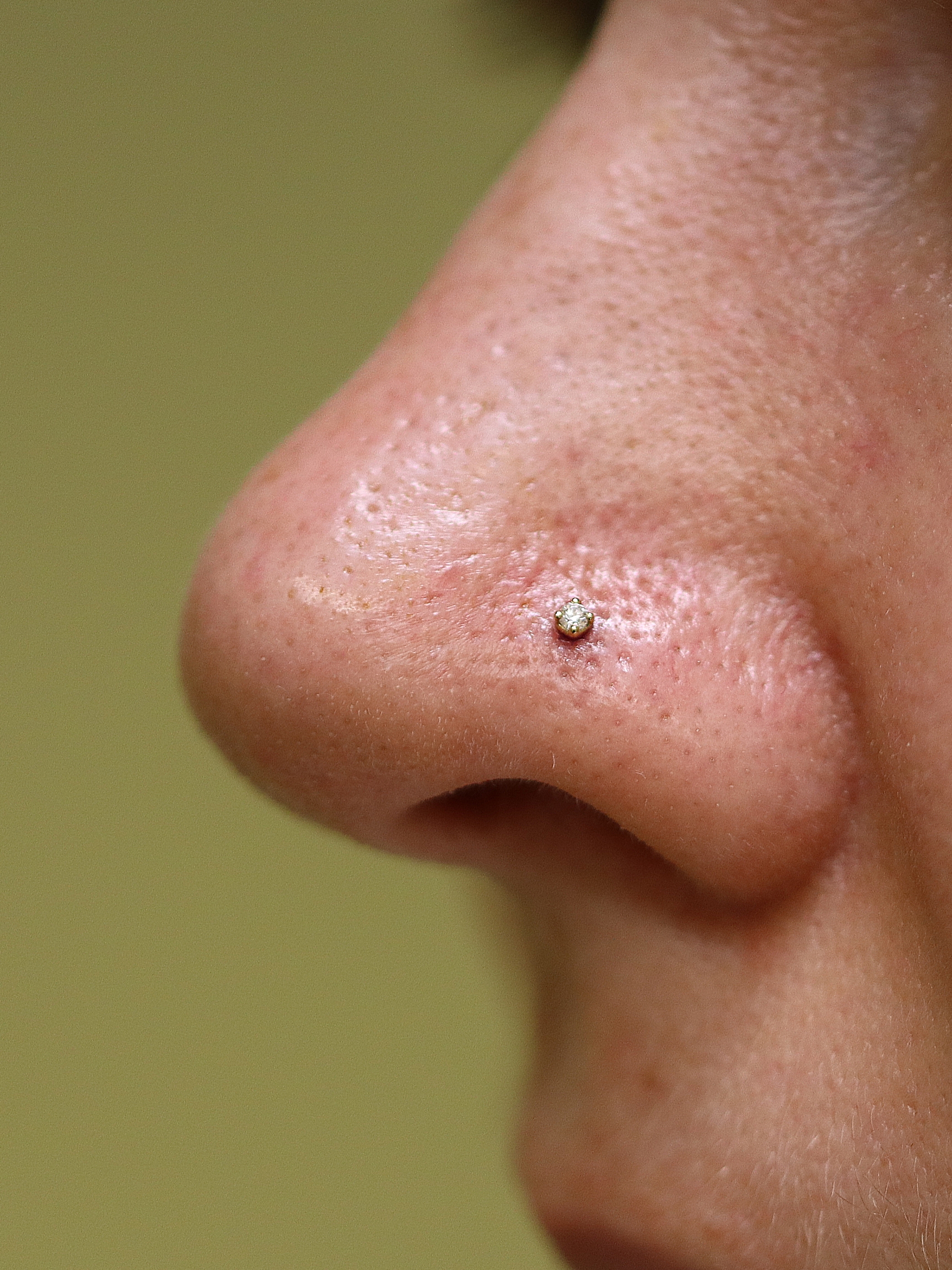 Nostril piercing with 1.5mm moissanite in 18k yellow gold setting from Ixus Fine Jewellery